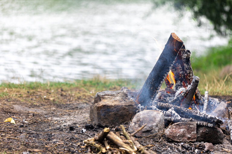 Small teepee fire setup on sticks above wet ground in rainy weather.